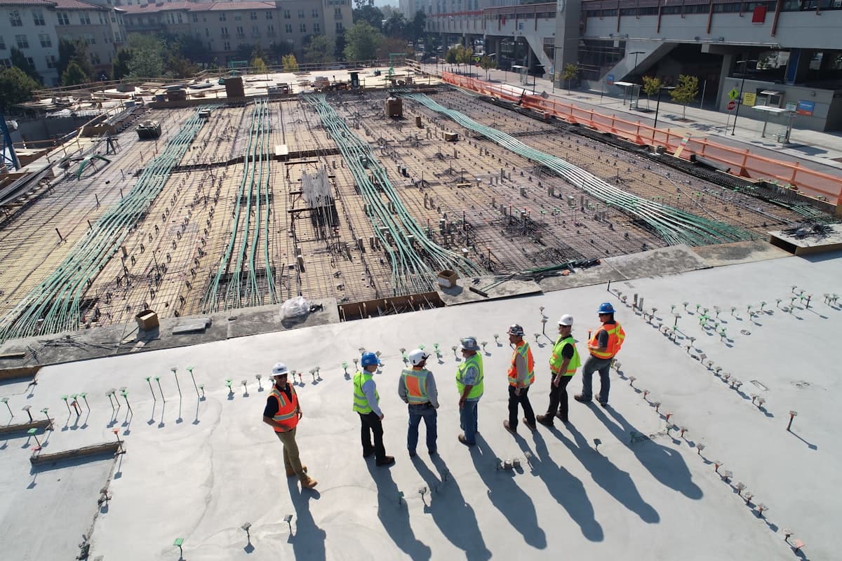 Aerial view of construction workers and managers reviewing a large building site