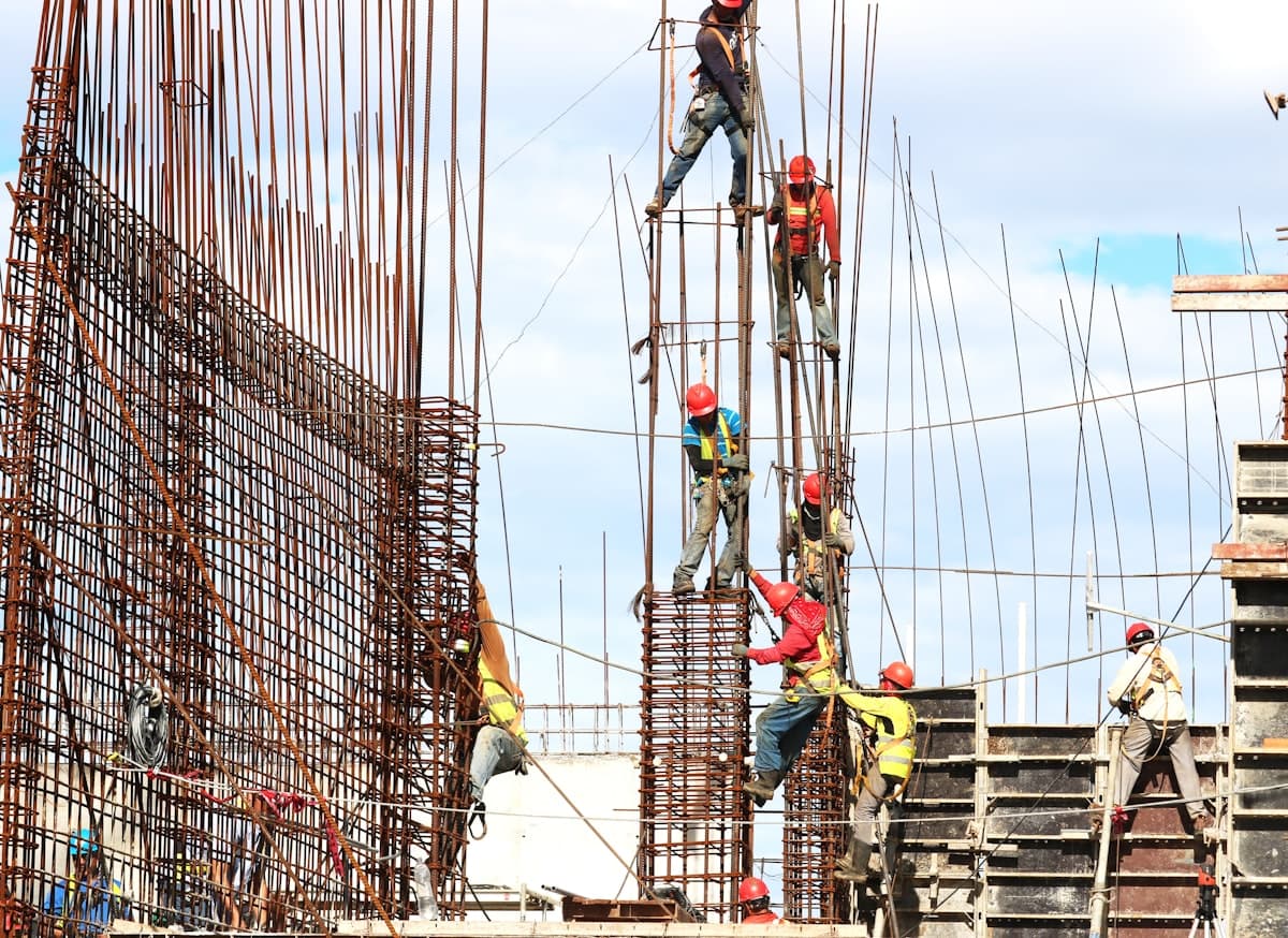 Construction workers in hard hats and safety vests working on steel reinforcement