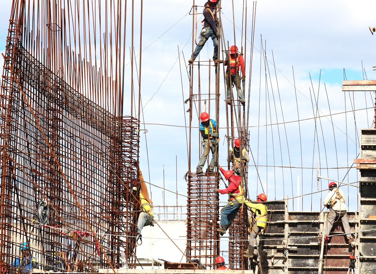 Construction workers in hard hats and safety vests working on steel reinforcement